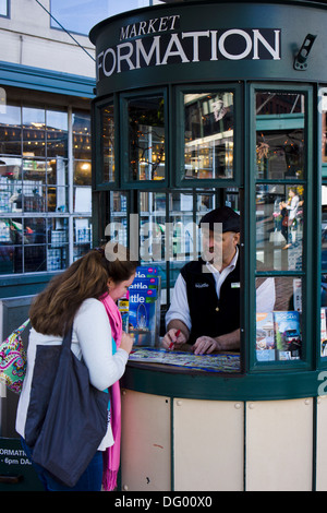 Female tourist making enquiries at tourist information booth at Pike Place Market. Seattle, Washington, USA. Stock Photo