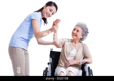 Female nursing worker helping senior man doing exercise Stock Photo