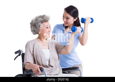 Female nursing worker helping senior woman doing exercise Stock Photo