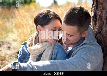 Outdoor close-up photo of young couple seated in grassy field. Stock Photo