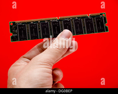 Hand holding computer ram isolated on red background Stock Photo