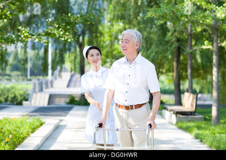 Senior man walking with walking frame under nurse's assistance Stock Photo