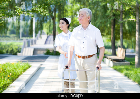 Senior man walking with walking frame under nurse's assistance Stock Photo