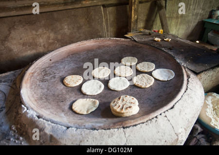 tortillas de maíz azul cociendose en comal de barro Stock Photo