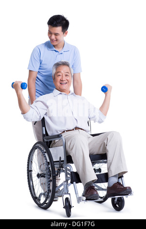 Male nursing worker helping senior man doing exercise Stock Photo