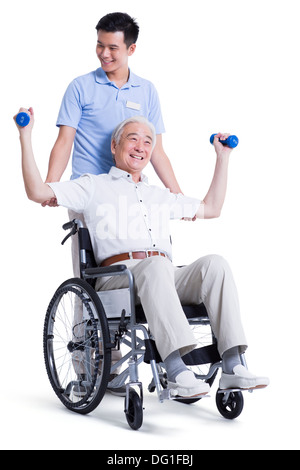 Male nursing worker helping senior man doing exercise Stock Photo