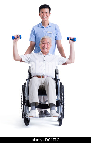 Male nursing worker helping senior man doing exercise Stock Photo