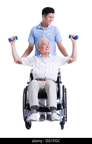 Male nursing worker helping senior man doing exercise Stock Photo