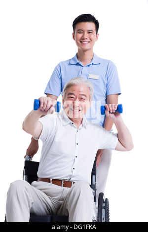 Male nursing worker helping senior man doing exercise Stock Photo