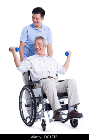 Male nursing worker helping senior man doing exercise Stock Photo