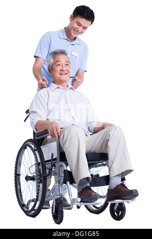Male nursing worker helping senior man doing massage on the back Stock Photo