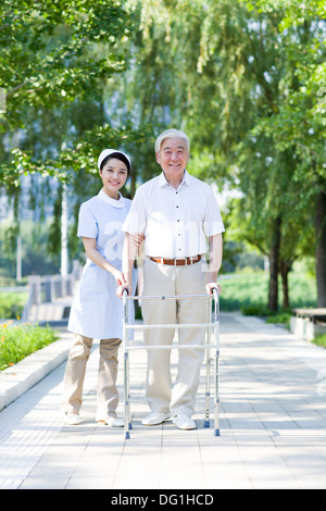 Senior man walking with walking frame under nurse's assistance Stock Photo