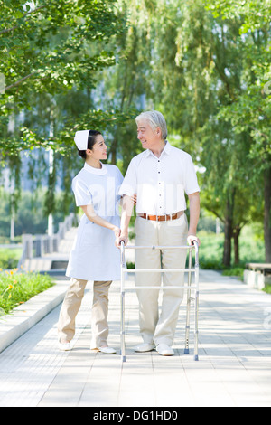 Senior man walking with walking frame under nurse's assistance Stock Photo