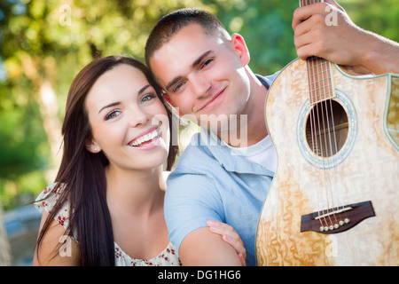 Affectionate Mixed Race Couple Portrait with Guitar in the Park. Stock Photo
