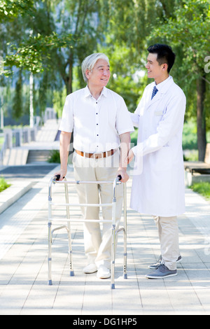 Senior man walking with walking frame under doctor's assistance Stock Photo