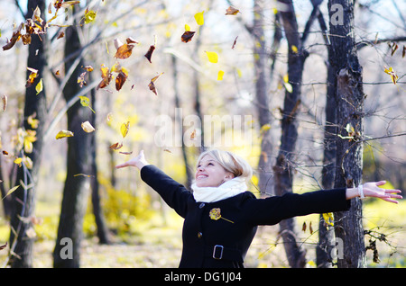 young woman in an autumn park throwing autumn leaves Stock Photo