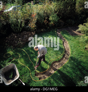 Birds-eye view of man digging out a new curved path in lawn Stock Photo