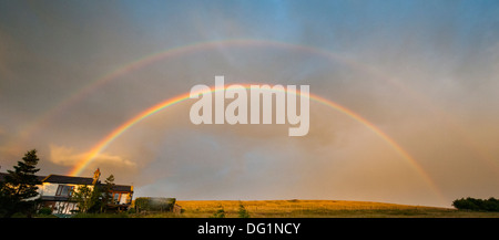 Double rainbow at sunset, against a cloudy sky over a Northumbrian dale. Stock Photo