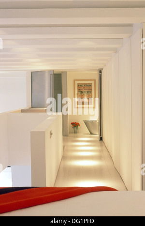 Open-plan landing and bedroom with white linen on bed in loft ...