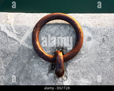 metallic and rusty mooring ring on dock Stock Photo