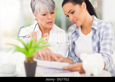 beautiful young woman helping her mother paying her bills Stock Photo