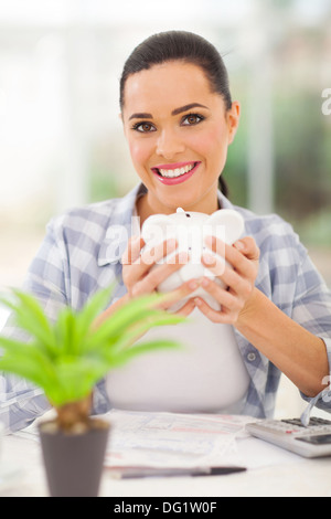 happy young woman holding piggyback and calculating savings Stock Photo