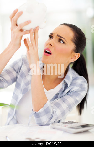 young woman emptying her piggybank savings with less in than expected Stock Photo
