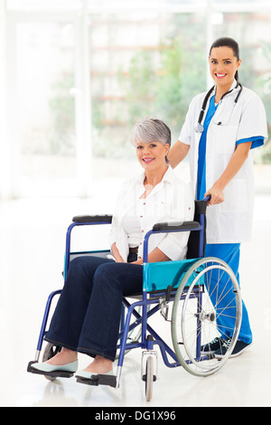 pretty young nurse pushing middle aged patient on wheelchair Stock Photo