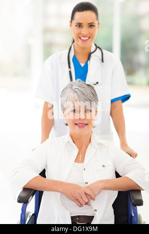 friendly medical nurse taking care of senior patient in wheelchair Stock Photo