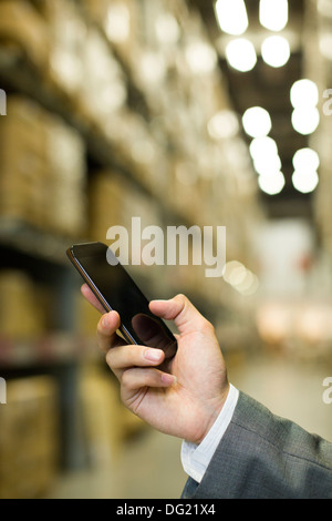 Businessman with smart phone in warehouse Stock Photo