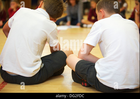 Two young school children sitting down in an assembly at a English primary school Stock Photo