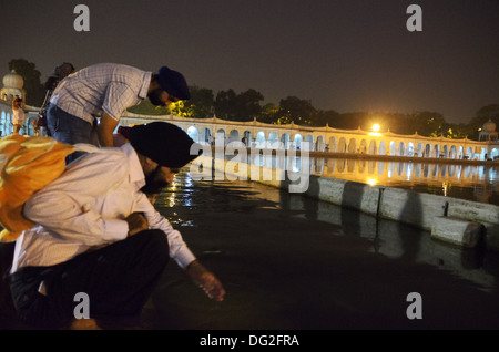 Sikh devotees ablution in the sacred pool in Gurdwara Bangla Sahib the most prominent Sikh temple in Delhi, India Stock Photo