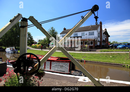 A narrowboat moored by the crane at Norbury Junction on the Shropshire Union Canal, the Junction Inn in the background Stock Photo