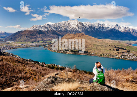 Queenstown, South Island, New Zealand. A photographer catches a plane taking off from Queenstown airport, with Lake Wakatipu below. Stock Photo