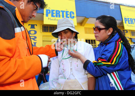 El Alto, Bolivia. 12th Oct, 2013.  A competitor is given a sweet (to increase blood sugar levels) and oxygen to help recover from the effects of exertion at high altitude after completing a Cholitas Bicycle Race for indigenous Aymara women. The race is held at an altitude of just over 4,000m along main roads in the city of El Alto (above the capital, La Paz) for Bolivian Womens Day, which was yesterday Friday October 11th. Credit:  James Brunker / Alamy Live News Stock Photo