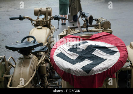 German motorbike and side-car, &  Nazi swastika flag at the ‘Railway in Wartime’  North Yorks Moors Railway (NYMR) event 2013.   Levisham Station, was decorated with period posters, & French signs  during the (NYMR) ‘Wartime Weekend’ to become  ‘Le Visham’ in northern France. The gathering, a recreation of a French village occupied by World War Two, World War II, Second World War,  WWII, WW2 German troops. The swastika is an ancient symbol that was in use in many different cultures for at least 5,000 years before Adolf Hitler adopted the flag Stock Photo