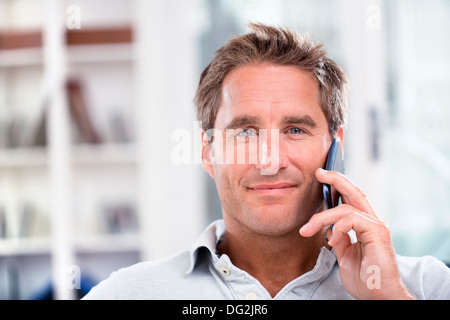 Happy mature male talking on mobile phone indoor Stock Photo