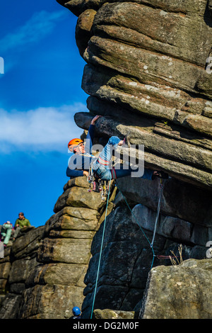 Male rock climber person doing a Heel hook on the crux of Flying Buttress Direct, Stanage, Peak District, UK Stock Photo