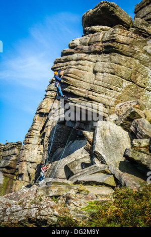 Men socialising - Two male climbers enjoying testing themselves on Flying Buttress Direct, Stanage, Peak District, UK Stock Photo