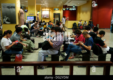 Chinese tourists overusing their gadgets at The Phnom Penh International Airport, Phnom Penh, Cambodia, Indochina. © Kraig Lieb Stock Photo
