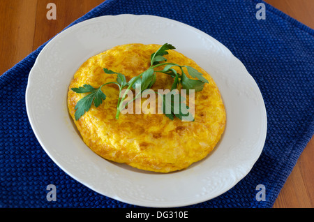 Spanish typical food; an omelette made with fried potatoes and (sometimes), onion . She is adorned with parsley leaves Stock Photo