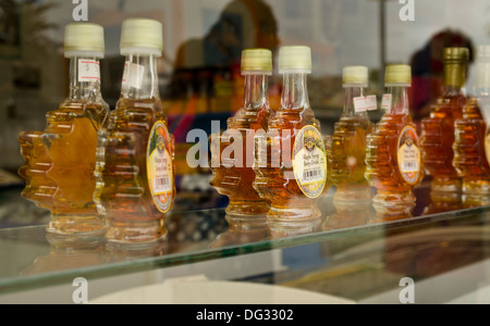 Maple leaf shaped jars of maple syrup sitting on a shelf in the window a Canadian tourist souvenir shop. Stock Photo