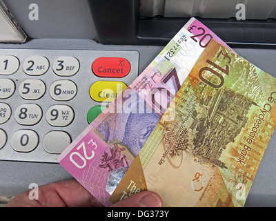 Scots Pound Sterling Notes being pulled from a Scottish Clydesdale bank ATM cash dispensing machine , Scotland UK Stock Photo