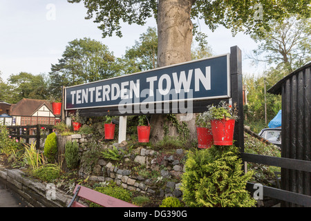 Sign on Tenterden Town railway station platform with decorative red fire buckets planted with flowers Stock Photo