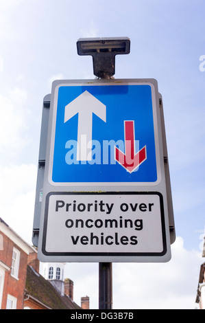 Priority over oncoming vehicles UK road traffic sign with white and red arrows on a blue background Stock Photo