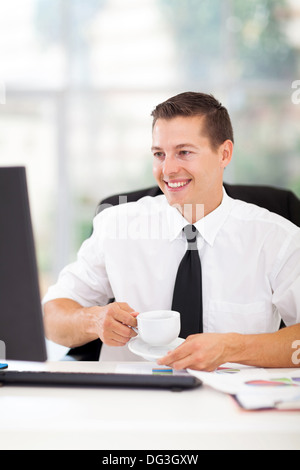 cheerful businessman drinking coffee while working on his computer in office Stock Photo