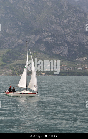 Couple sailing yacht on Lake Garda, Italy. Yacht is carrying Italian and German flags. Stock Photo