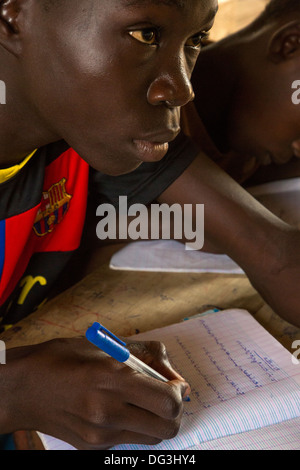 Senegal, Touba. Boy at Al-Azhar Madrasa, a School for Islamic Studies, writing in Arabic in his notebook. Stock Photo