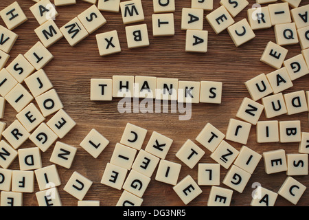 Plastic letters from a childrens' spelling game on a wooden table spell 'thanks' Stock Photo