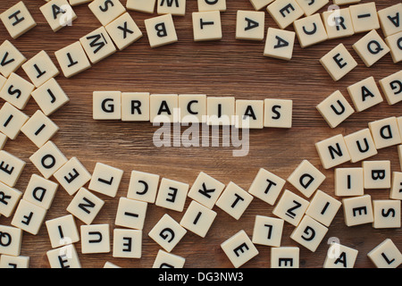 Plastic letters from a childrens' spelling game on a wooden table spell 'Gracias' Stock Photo